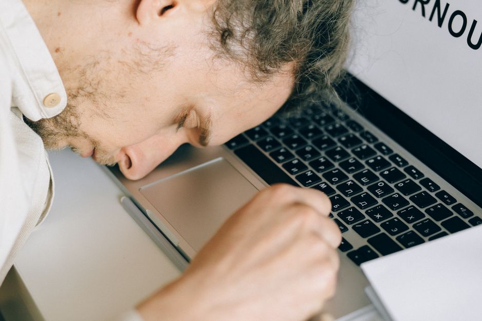 A person looking exhausted and burnt out in front of a computer.