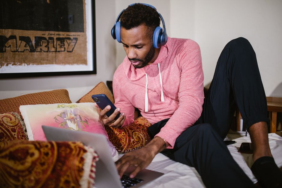 Person lying in bed using a mobile phone to remote control a desktop computer