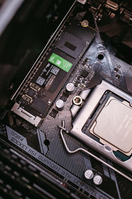 Computer internal hardware showing CPU, RAM sticks and NVMe SSD installed on motherboard