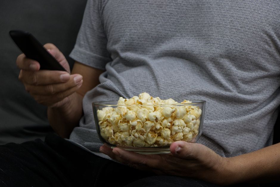 Bored viewer with remote control and popcorn