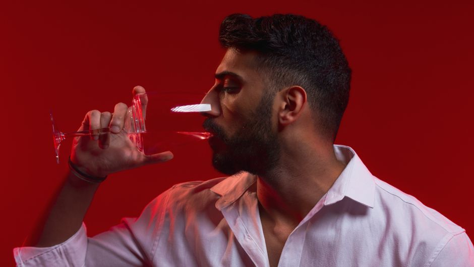 Close up of someone slowly sipping white wine from a small glass.