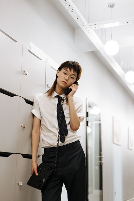 职员佩戴蓝牙耳机在办公室走廊边走边讲电话